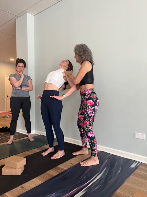 yoga instructor helping student with back bend pose