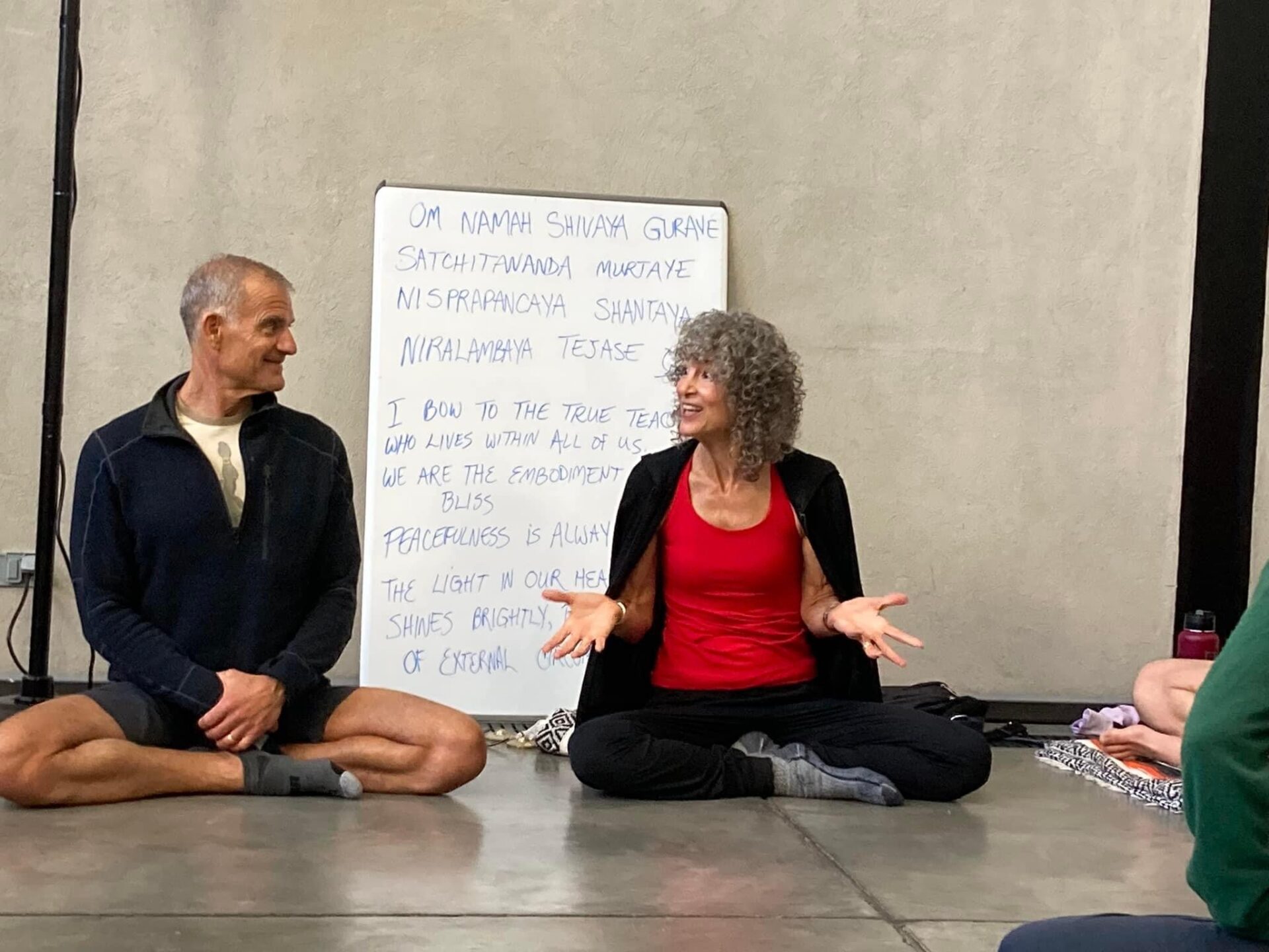 two yoga instructors sitting on the floor leading a workshop