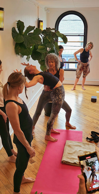 yoga student receiving an assist from Desiree Rumbaugh